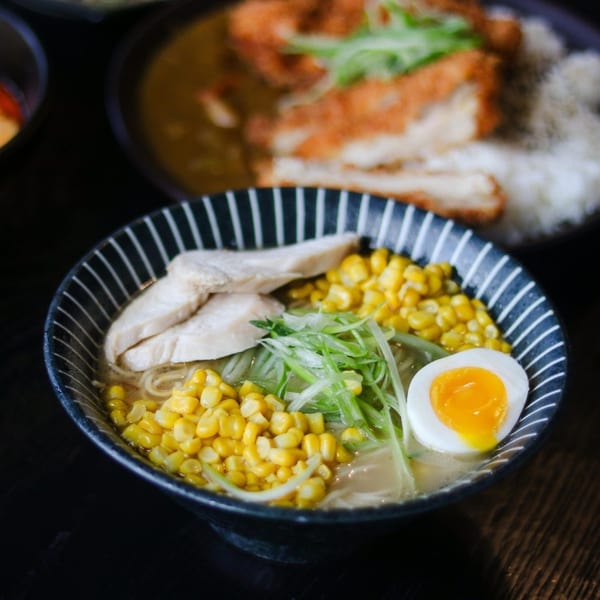 Boru Ramen's chicken ramen with corn, scallions, and a soft-boiled egg in a striped bowl.