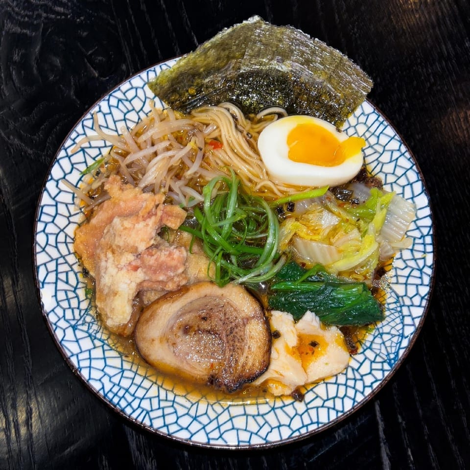 A bowl of Boru Ramen with noodles, pork, egg, seaweed, bean sprouts, and greens.