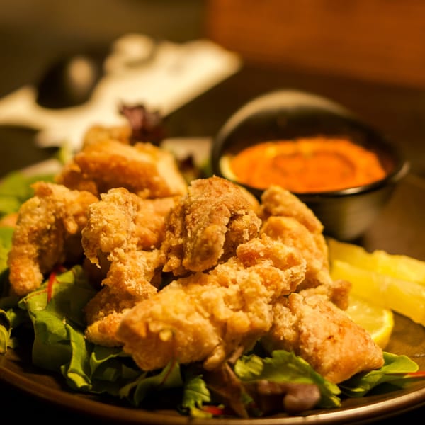 Crispy Boru Ramen fried chicken karaage on a bed of lettuce with lemon wedges and a dipping sauce.