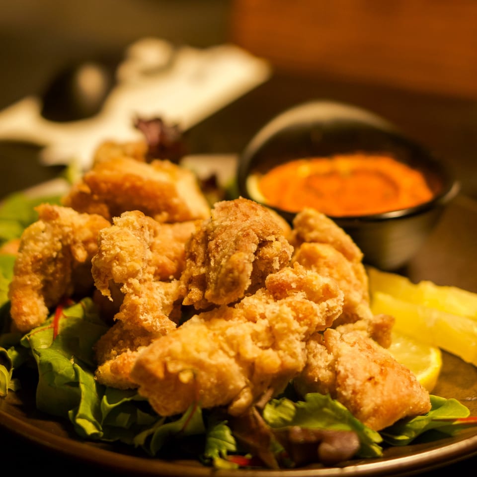 Crispy Boru Ramen fried chicken karaage on a bed of lettuce with lemon wedges and a dipping sauce.