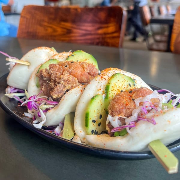 Three Boru Ramen fried chicken bao buns with cucumber, cabbage, and sesame seeds.