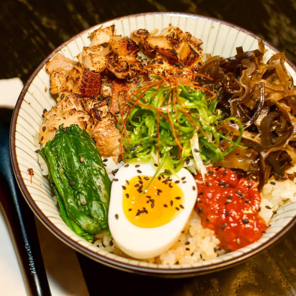 A Boru Ramen bowl with grilled pork, seaweed, soft-boiled egg, and spicy sauce over rice.