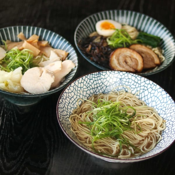 Three bowls of Boru Ramen, two with various toppings and one with plain noodles and scallions.