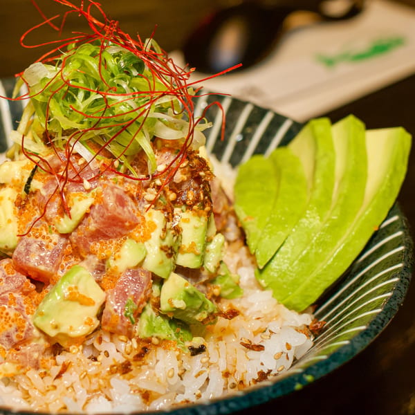Close-up of a Boru Ramen poke bowl with tuna, avocado, roe, green onions, and red chili threads.