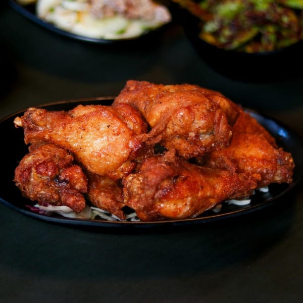 Crispy, golden-brown Boru Ramen fried chicken wings on a black plate with shredded cabbage.
