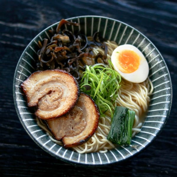 A bowl of Boru Ramen with pork belly, soft-boiled egg, green onions, and mushrooms.