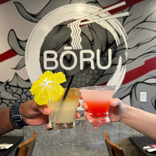Two hands holding colorful cocktails, one yellow with an umbrella, against a Boru Ramen logo.