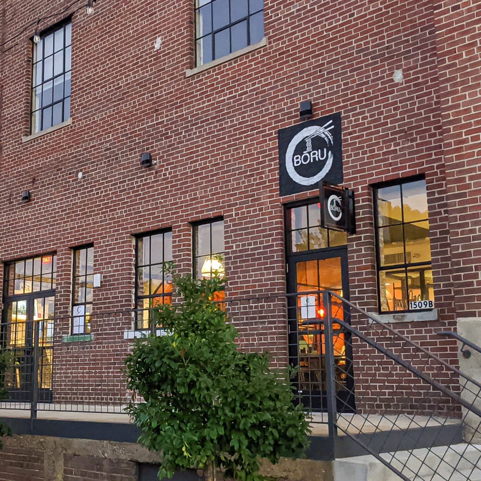 Exterior of Boru Ramen restaurant, a brick building with large windows and a black sign.