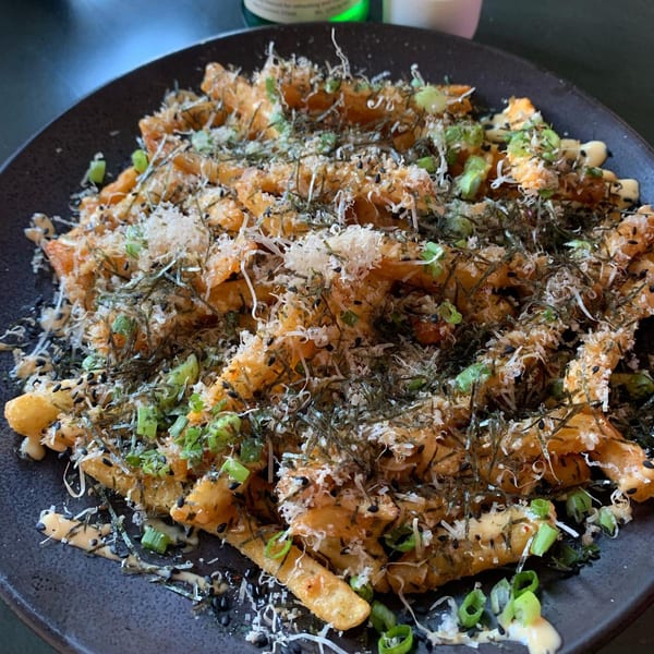 Boru Ramen's Japanese fries topped with seaweed, sesame seeds, green onions, and white sauce.
